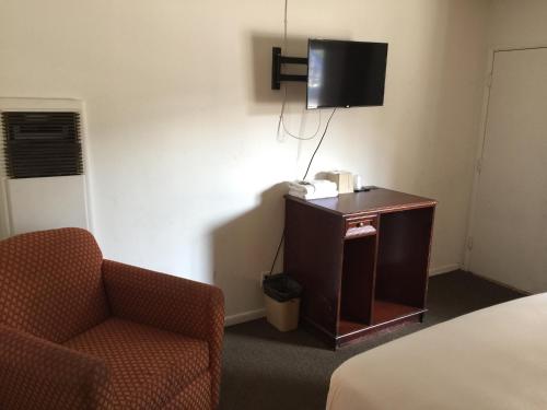 a hotel room with a chair and a television at Holiday Lodge in Los Angeles