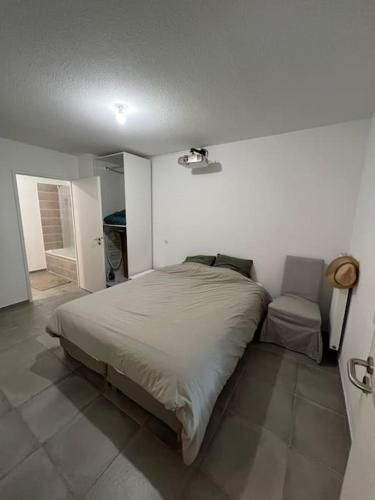 une chambre avec un lit et une chaise dedans dans l'établissement Appt à 10 min de la place comédie Montpellier, à Castelnau-le-Lez