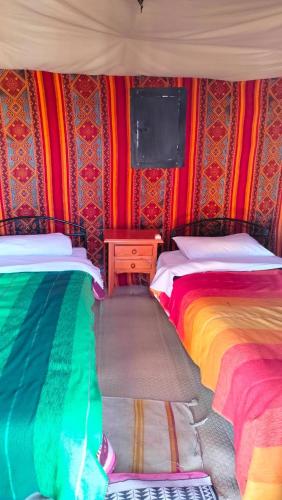 two beds in a room with colorful walls at Merzouga wild Camp in Merzouga