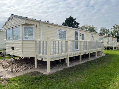 a large white mobile home with a wooden porch at Goodwin's static caravan in Mablethorpe
