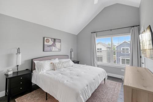a white bedroom with a bed and a window at A Touch of Grey in Ottawa