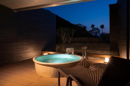 a bathroom with a bath tub with a table and chairs at Hotel Tokinoza in Kihokucho