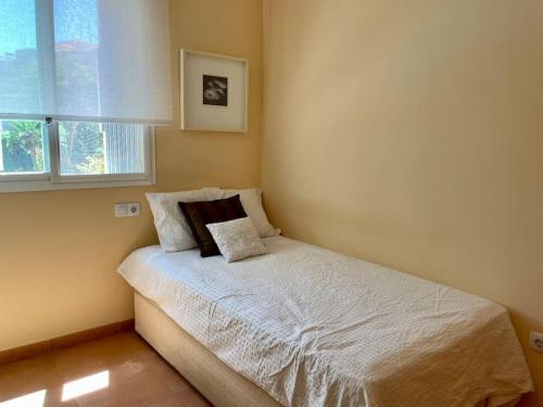 ein kleines Schlafzimmer mit einem weißen Bett und einem Fenster in der Unterkunft Agradable adosado con piscina y jardín in Canet d'en Berenguer