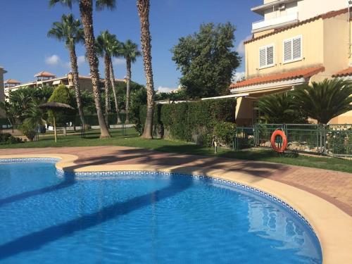 ein Swimmingpool vor einem Gebäude mit Palmen in der Unterkunft Agradable adosado con piscina y jardín in Canet d'en Berenguer