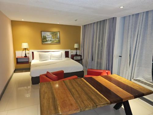 a hotel room with a bed and a table at Golden Tree Hotel Belize in Belize City