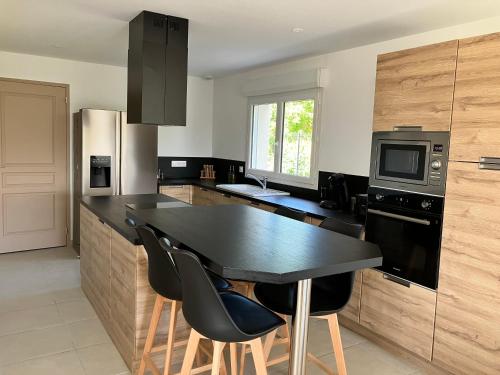 - une cuisine avec un comptoir noir et des chaises dans l'établissement Au pied des batteries, à Longues-sur-Mer