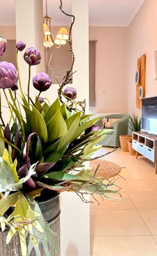 a vase filled with purple flowers in a living room at Petite Fleur in Preveza