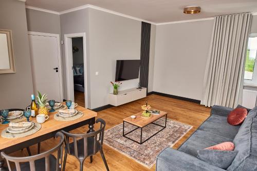 a living room with a table and a blue couch at Babichy 29 DOM Apartamenty MANDORIA , Rodzina , Family , Orientarium , PTAK , Parking bezpłatny in Babichy
