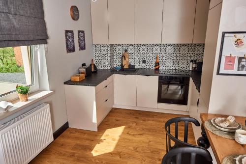 a kitchen with white cabinets and a black counter top at Babichy 29 DOM Apartamenty MANDORIA , Rodzina , Family , Orientarium , PTAK , Parking bezpłatny in Babichy