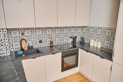 a kitchen with a black and white tiled wall at Babichy 29 DOM Apartamenty MANDORIA , Rodzina , Family , Orientarium , PTAK , Parking bezpłatny in Babichy
