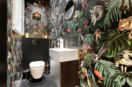 La salle de bains est pourvue d'un lavabo et d'un papier peint tropical. dans l'établissement Appartement spacieux et élégant - Grds Boulevards, à Paris