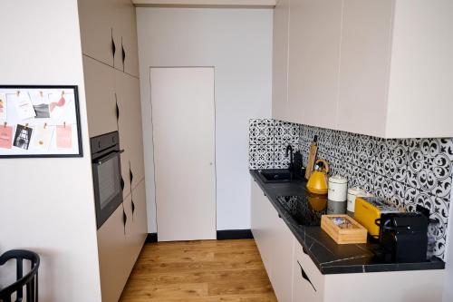 a kitchen with white cabinets and black and white tiles at Babichy 29 DOM Apartamenty MANDORIA , Rodzina , Family , Orientarium , PTAK , Parking bezpłatny in Babichy