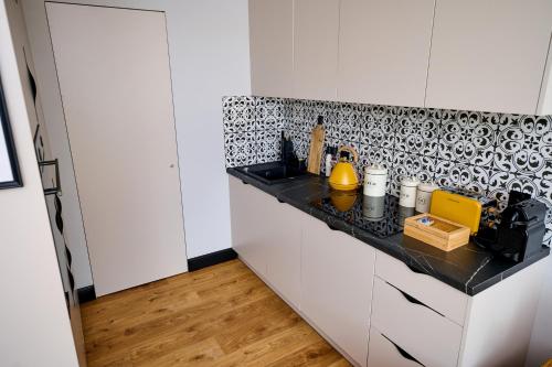 a kitchen with black and white tile on the wall at Babichy 29 DOM Apartamenty MANDORIA , Rodzina , Family , Orientarium , PTAK , Parking bezpłatny in Babichy