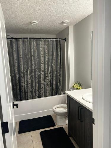 a bathroom with a toilet and a shower curtain at Praise bethel -Homely walkout legal basement in YYC in Calgary