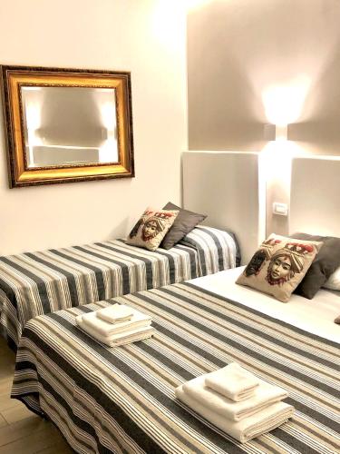 two beds in a room with a mirror and towels at B&B Giulia in Taormina