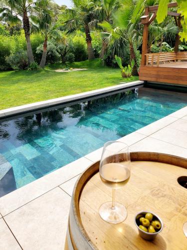 a glass of wine sitting on a table next to a swimming pool at Luxury Bali Villa in Hossegor 5 stars- Pool & Petanque in Hossegor