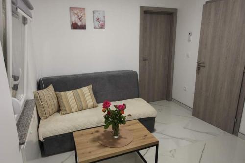 a living room with a couch and a table with flowers at Apartmani Venecia in Prozor