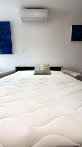 - un lit blanc avec un oreiller dans l'établissement Charmant studio au calme avec piscine, à Lespignan