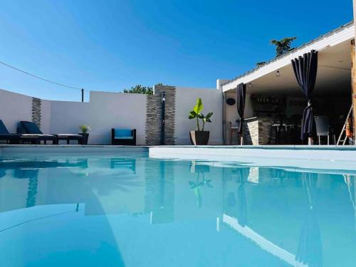 une piscine avec de l'eau bleue devant une maison dans l'établissement Charmant studio au calme avec piscine, à Lespignan