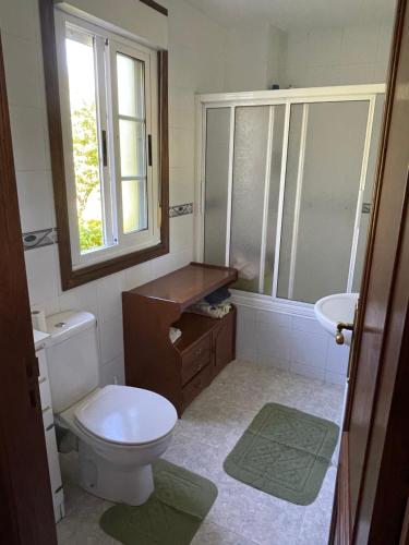 a bathroom with a toilet and a sink and a window at La Fincurri del Nando in A Coruña
