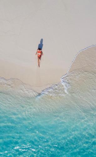 a person walking on the beach near the water at Ostrov Palm in Ukulhas