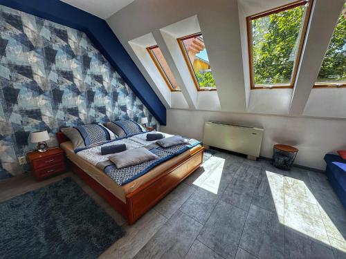 a bedroom with a bed with blue walls and windows at Corso Apartman Hajdúszoboszló in Hajdúszoboszló