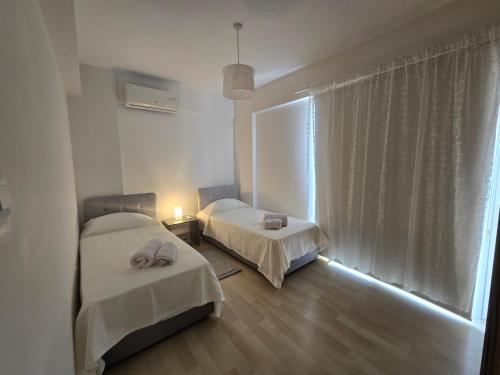 two beds in a room with a window at Lake View Apartment in Famagusta in Mağusa