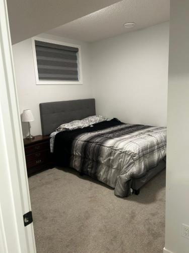 a bedroom with a bed and a table and a window at Praise bethel -Homely walkout legal basement in YYC in Calgary