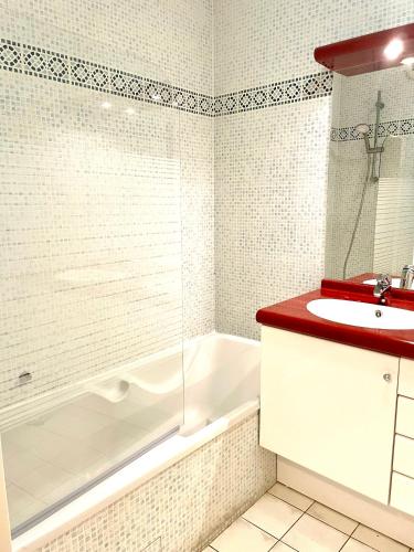 une salle de bain avec une baignoire blanche et un lavabo dans l'établissement Appartement Cannes avec piscine, à Cannes