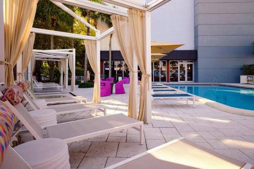 a pool with white lounge chairs next to a swimming pool at Aloft Miami Dadeland in Kendall