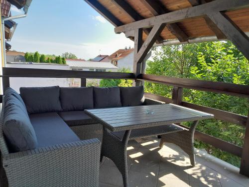 a patio with a couch and a table on a deck at Apartman kod dide i bake in Vukovar