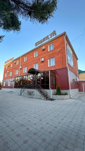a large red brick building with a sign on it at Достык Люкс in Kostanay