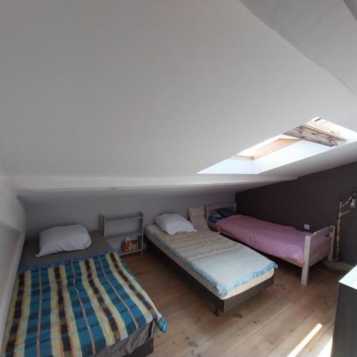 une chambre mansardée avec deux lits et une fenêtre dans l'établissement Coquette maison, 2 chambres mansardées, Narbonne Plage, à Narbonne-Plage