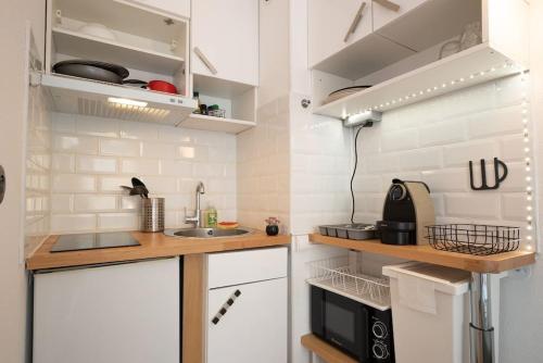 une petite cuisine avec des armoires blanches et un évier dans l'établissement Cocon Urbain - Près de la Gare, à Nice