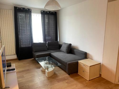 un salon avec un canapé et une table en verre dans l'établissement Apartment, à Épinay-sur-Seine