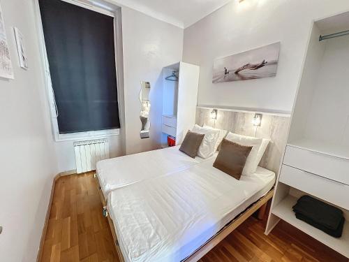 une petite chambre avec un lit blanc et une fenêtre dans l'établissement ROL2 - Beau 2 pièces avec balcon et vue mer latérale, à Cannes