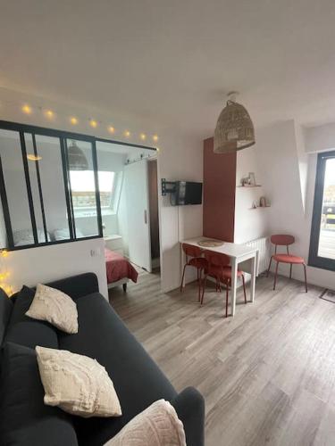 un salon avec un canapé noir et une table dans l'établissement Studio Vue Mer, à Villers-sur-Mer