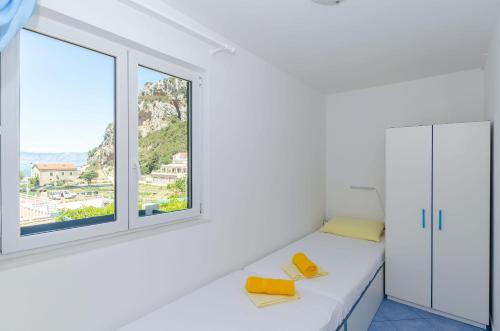 a white room with a bed and two windows at Apartments Vidoni in Zastražišće