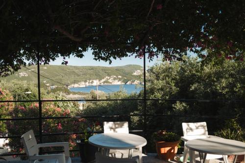 two tables and chairs on a patio with a view at Ulisse Apartments in Paleokastritsa