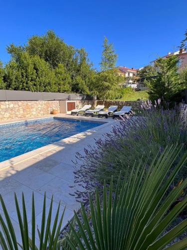 a swimming pool with lounge chairs next to a garden at Vila Palma in Vrbnik