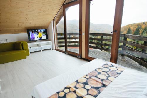a bedroom with a bed and a tv and a balcony at Mountain Apartments SuperSki in Cavnic