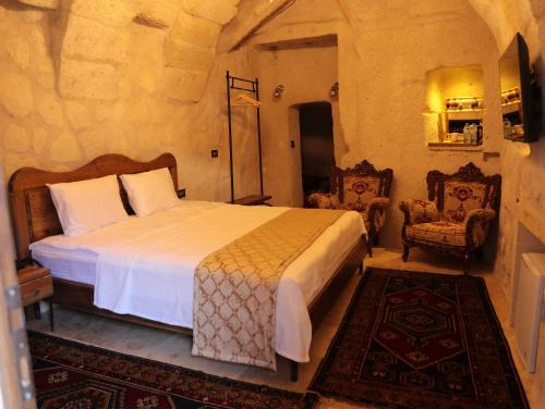 a bedroom with a bed and two chairs at Hira Cave Hotel in Goreme