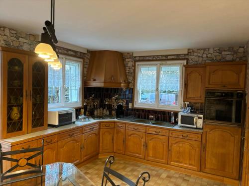 une grande cuisine avec des placards en bois et des fenêtres dans l'établissement Agréable maison de ville avec tout à proximité, à Saint-Dizier