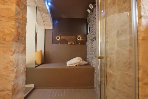 ein Badezimmer mit Dusche und einer Bank mit Spiegel in der Unterkunft Dama Your Luxury Stay in Castellana Grotte