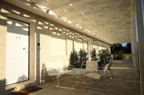 d'une terrasse avec des chaises blanches et une table en verre. dans l'établissement SUNSEA - Enjoy Your Family, à Capo Vaticano