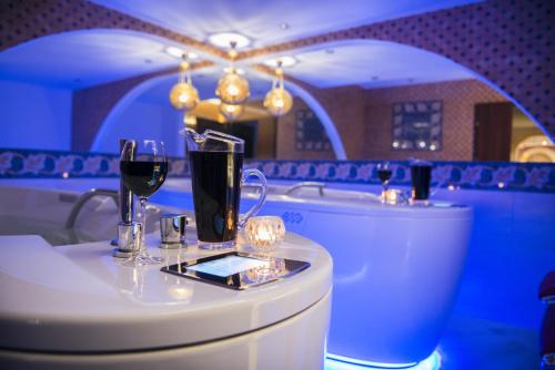 a bath tub with two glasses of wine on a table at Villa Andalucia SPA & Leisure in Ciechocinek