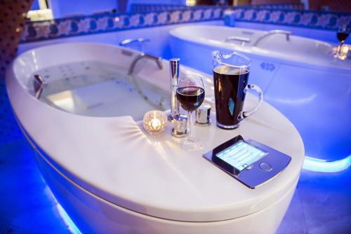 a bath tub with two glasses of wine and a tablet at Villa Andalucia SPA & Leisure in Ciechocinek