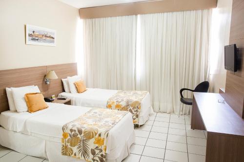 a hotel room with two beds and a television at Rede Andrade Barra in Salvador