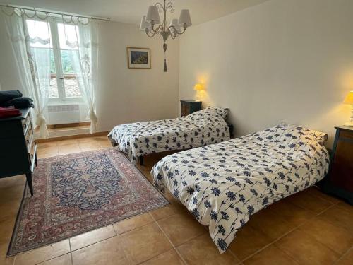 une chambre avec deux lits et un tapis dans l'établissement Maison des hirondelles petit Luberon, à Niozelles