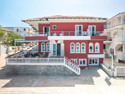a red building with a balcony on a street at Summer Beach Hotel in Polykhrono